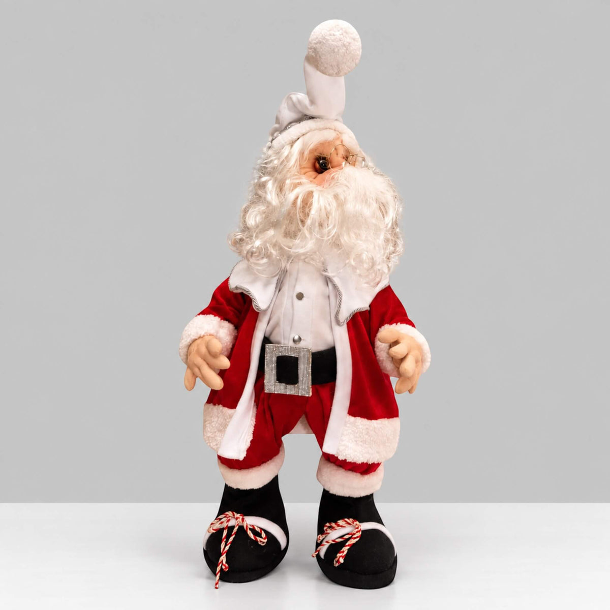 Full-length side view of handmade Santa Claus wearing a red suit, white hat, and black boots.