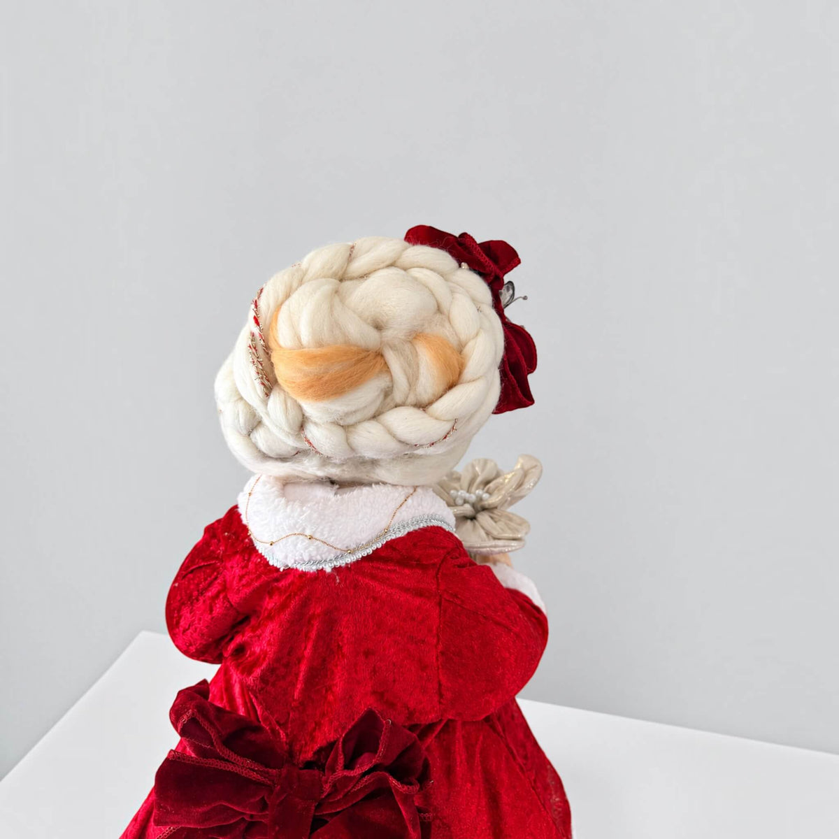 Rear close-up of Mrs. Claus showing her braided white hair and red dress bow.