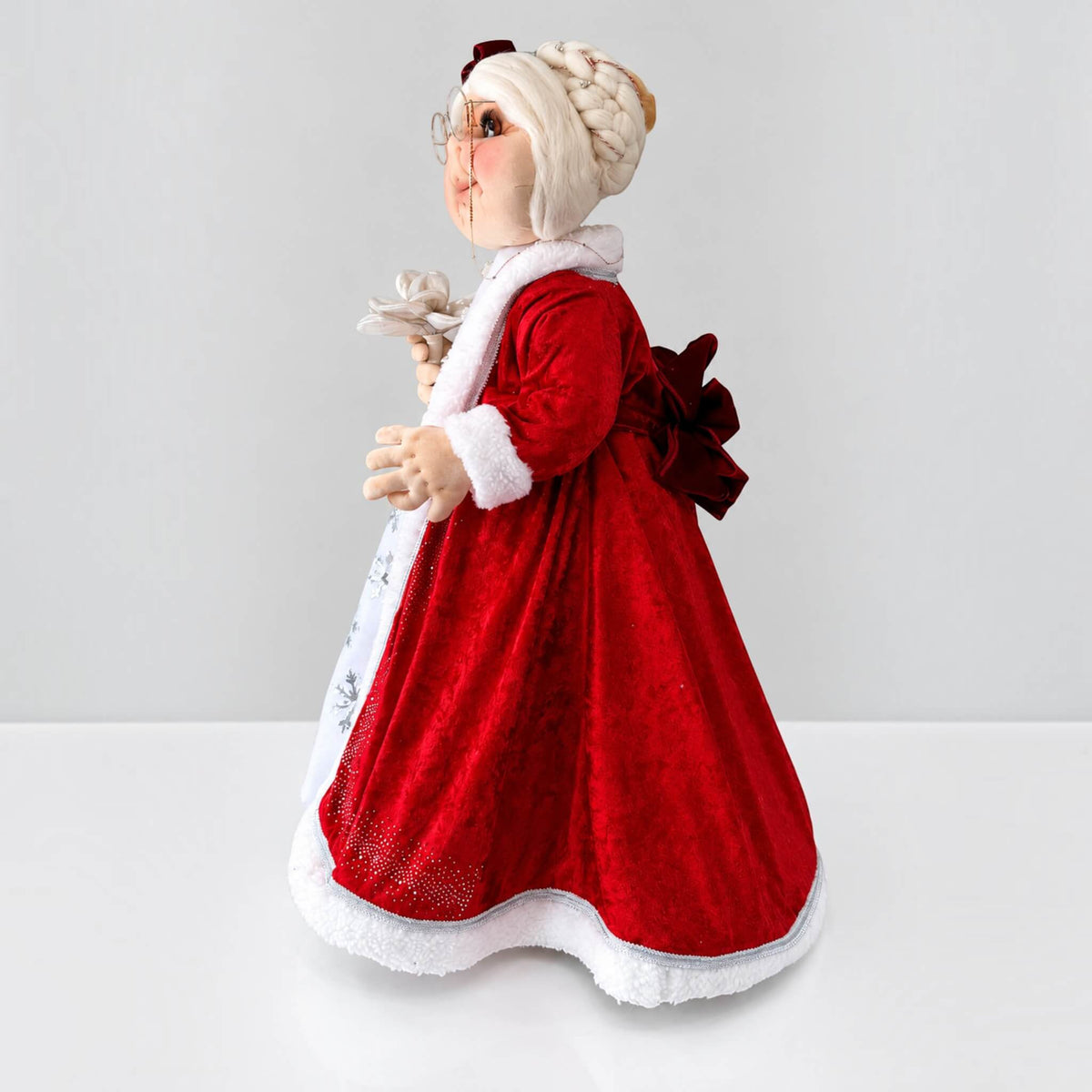 Side profile of handmade Mrs. Claus showing her glasses, white hair, and flowing red dress.