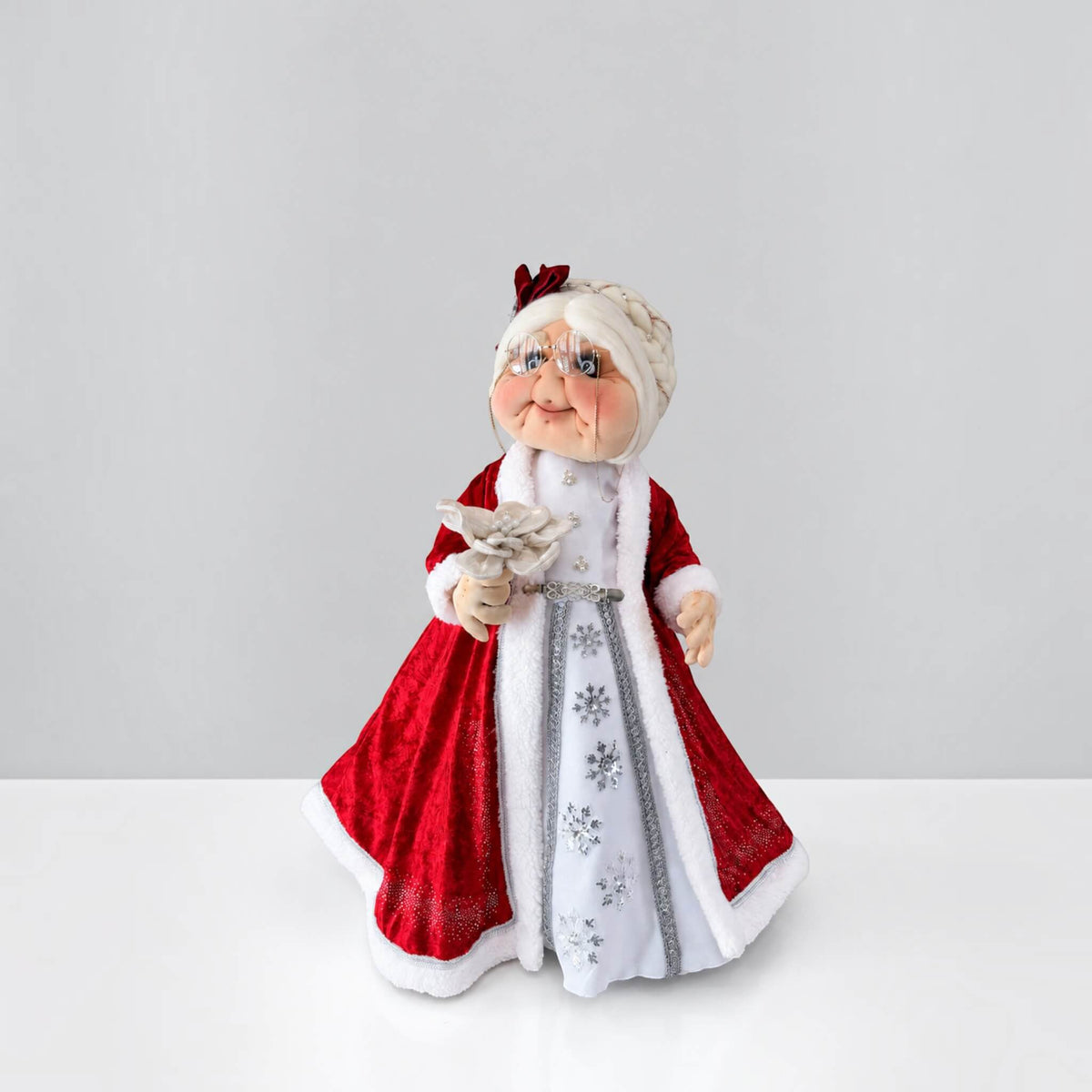 Full-length three-quarter view of Mrs. Claus wearing a red Christmas dress with white trim.