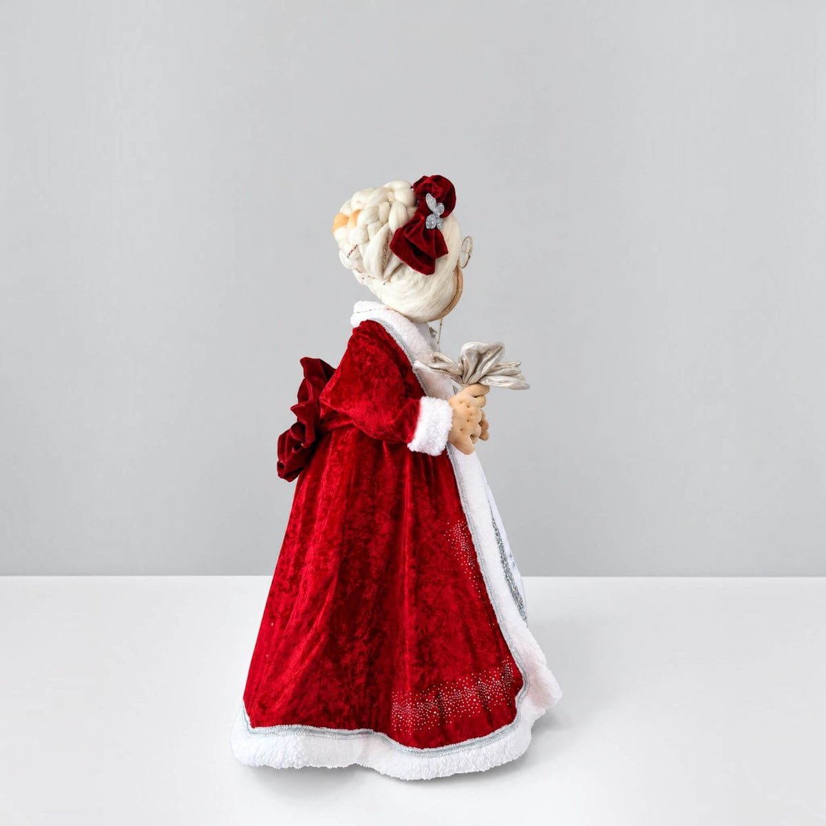 Side view of Mrs. Claus showing the shape of her red dress, white trim, and flower accessory.