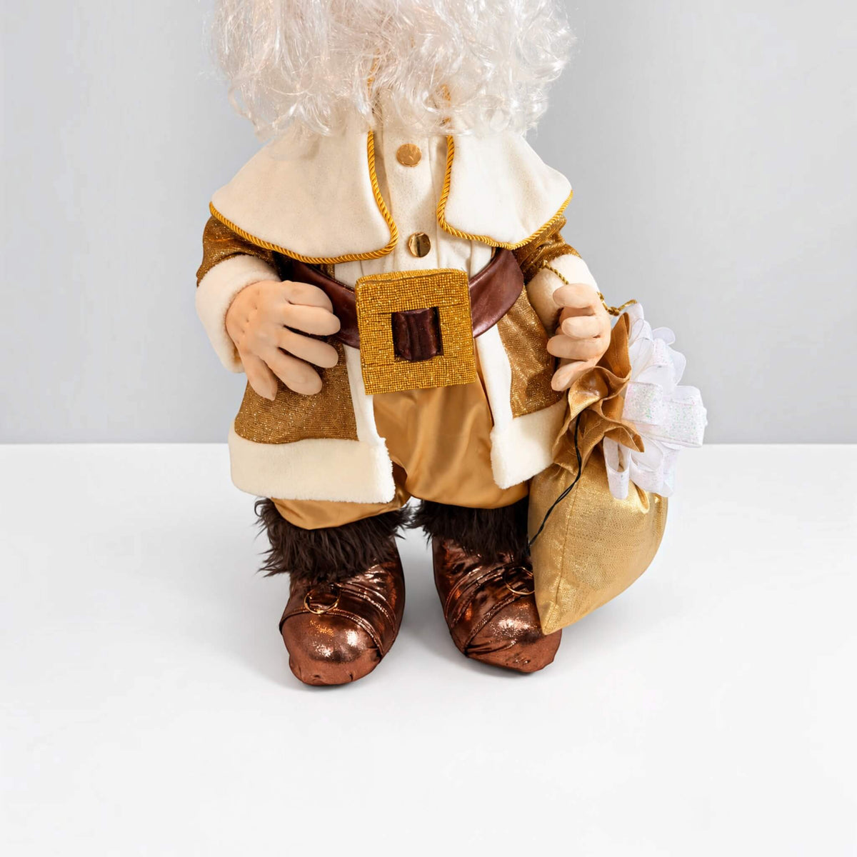 Close-up of gold Santa Claus showing his cream coat, gold belt buckle, brown boots, and gift bag.