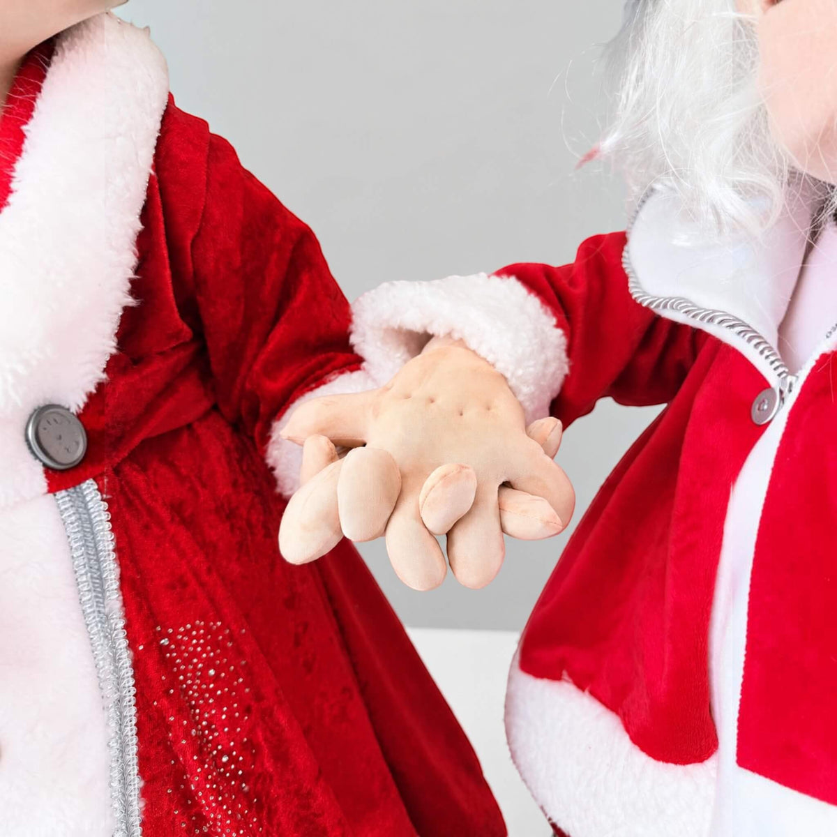 Close-up of handmade Mrs. Claus with white hair, glasses, rosy cheeks, a red bow, and a silver flower.