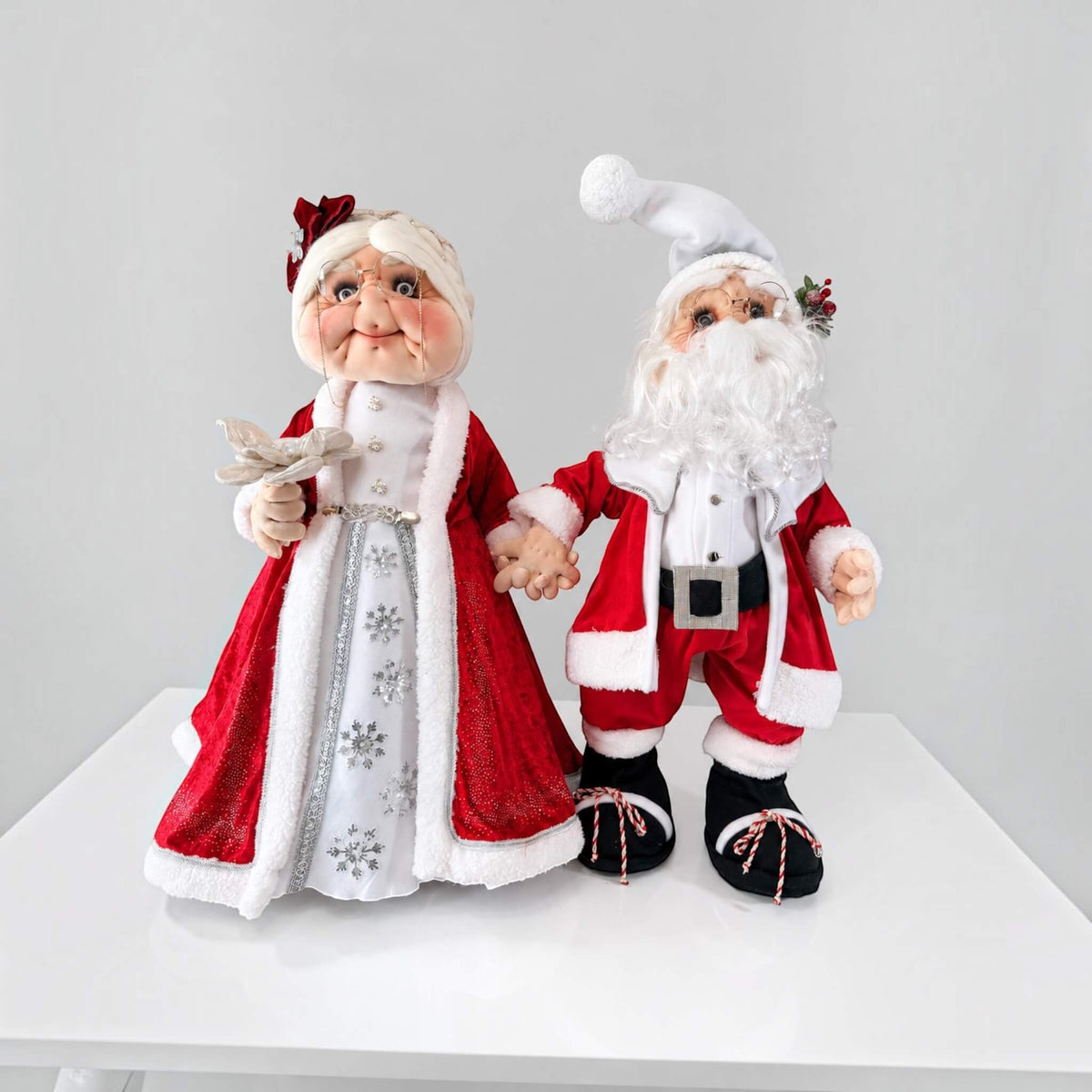 Angled close-up of Mrs. Claus showing her glasses, handcrafted face, white hair, and red headpiece.