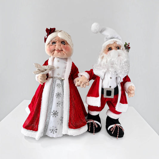 Full front view of handmade Mrs. Claus in a red and white Christmas dress, holding a silver flower.