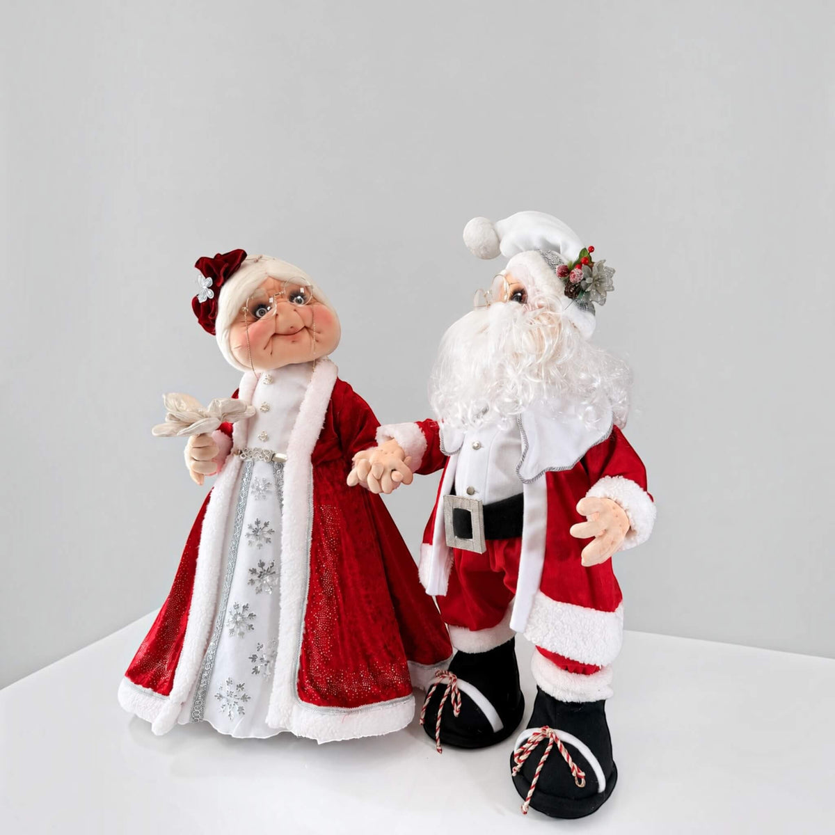 Close-up of Mrs. Claus holding a silver flower, with white trim and silver details on her red dress.